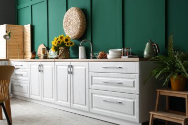 Mutfağın içinde mutfak aletleri ve beyaz tezgahlar var.