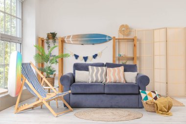 Sörf tahtası ve farklı plaj aksesuarları olan şık bir oturma odası.