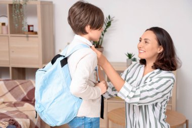 Anne oğlunu oturma odasında okula hazırlıyor.