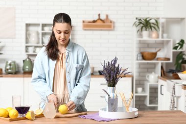Mutfaktaki masada lavantalı limonata hazırlamak için limon kesen genç bir kadın.