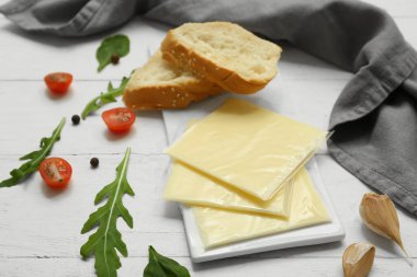 Lezzetli işlenmiş peynir, ekmek ve taze domateslerle dolu beyaz ahşap masa.