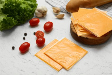 Lezzetli işlenmiş peynir dilimleri ve beyaz grunge masasında taze sebzeler.