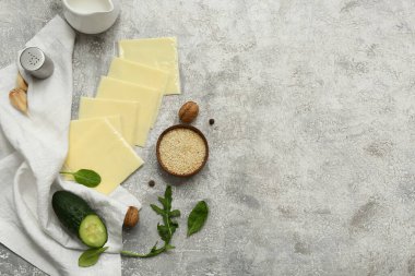 Gri grunge masasında taze yeşillik ve lezzetli işlenmiş peynir dilimleri.