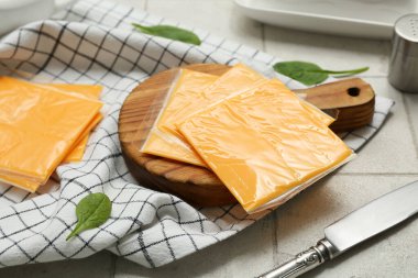 Lezzetli işlenmiş peynir dilimleri ve gri fayanslı masada ıspanak.