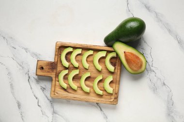 Beyaz arka planda taze olgun avokado parçaları olan ahşap tahta.