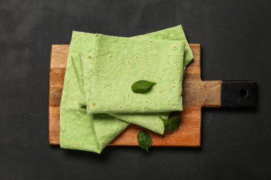 Ahşap tahta, yeşil lavaş ve siyah arka planda ıspanak.