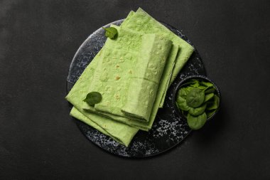 Siyah arka planda taze lavaş ve bir kase ıspanak.