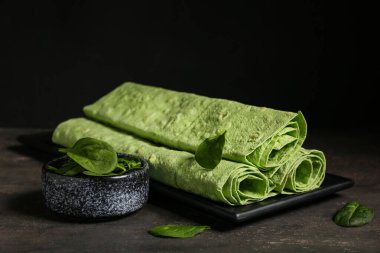 Yuvarlak yeşil lavaş ve siyah grunge masasında bir kase ıspanak.