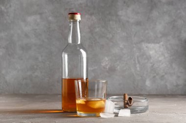 Şişe ve bir bardak soğuk rom ve puro gri arka planda kül tablasında. Yakın çekim.