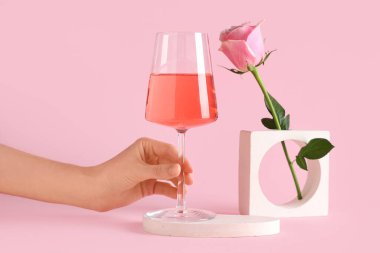 Pembe şaraplı kadın eli ve arka planda güzel bir gül.