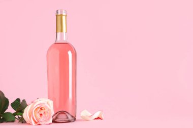Bir şişe pembe şarap ve arka planda güzel bir gül.