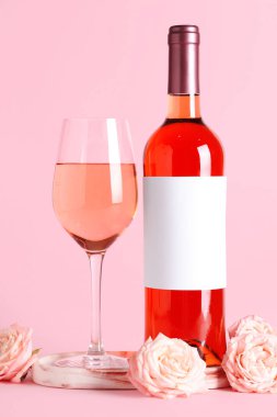 Bir bardak pembe şarap ve arka planda güzel güller.