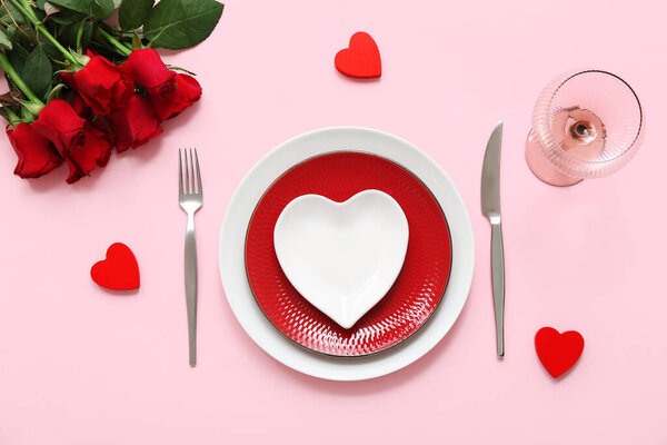 Стол с сердцами и красными цветами на розовом фоне. Празднование Дня Святого Валентина