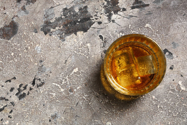 Glass of cold rum on grey grunge background. Top view