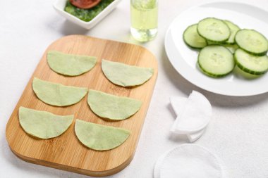 Beyaz arka planda pamuk göz altı bantları ve salatalık dilimleri olan tahta, yakın plan.