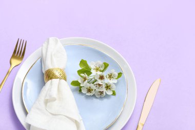 Katlanmış peçeteli ve çiçek açan ağaç dallı güzel masa ortamı.