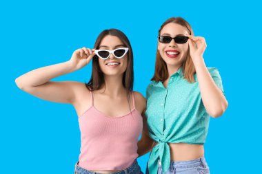 Mavi arka planda güneş gözlüklü bayan arkadaşlar