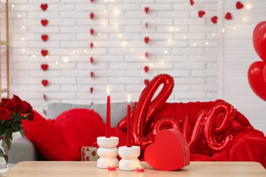 İçinde mumlar ve kelime şeklinde balonlar olan hediye kutusu. Sevgililer Günü kutlaması için süslenmiş masadaki aşk kelimesi.