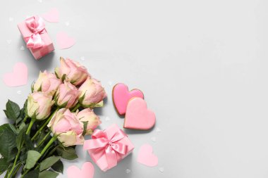 Gül buketi, hediye kutuları ve gri arka planda kalp şeklinde kurabiyeler. Sevgililer Günü kutlaması