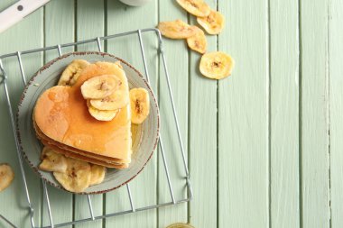 Kalp şeklinde lezzetli gözlemeler ve yeşil ahşap zemin üzerinde kurutulmuş muz tabağı. Sevgililer Günü kutlaması