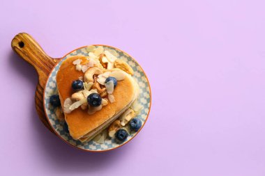 Kalp şeklinde leziz krepler, mor arka planda yabanmersini ve fındık. Sevgililer Günü kutlaması