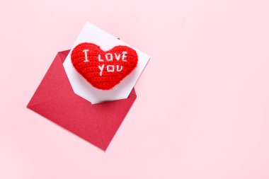 Zarflı kompozisyon, kart ve pembe arka planda kırmızı kalp. Sevgililer Günü kutlaması