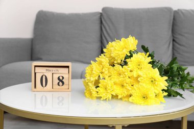Oturma odasındaki sehpanın üzerinde takvim olan sarı çiçekler. Uluslararası Kadınlar Günü kutlamaları