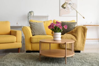 Oturma odasındaki masada pembe laleli vazo.