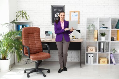 Ofisin yakınında dizüstü bilgisayar kullanan kadın bir ofis çalışanı.