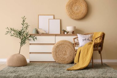 Güzel oturma odasının içinde çekmeceler, rahat koltuklar, resimler ve zeytin ağacı var.