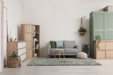 Konforlu kanepe, raf ünitesi, çekmece sandığı ve oturma odasının içindeki kahve masası.