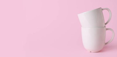 Pembe arkaplanda beyaz seramik bardaklar metin için boşluk
