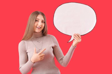 Kırmızı arkaplandaki boş konuşma balonuna işaret eden genç bir kadın.