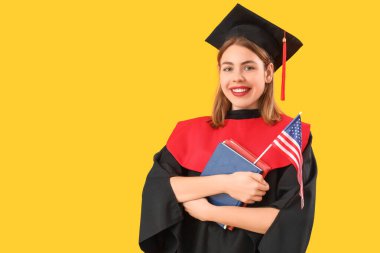 Amerikan bayrağı ve sarı arka plan kitapları olan kadın mezun.