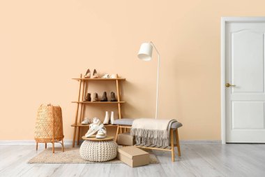 Raflar farklı şık kadın ayakkabılarıyla, bankta, lambada ve odada bej duvarın yanında.