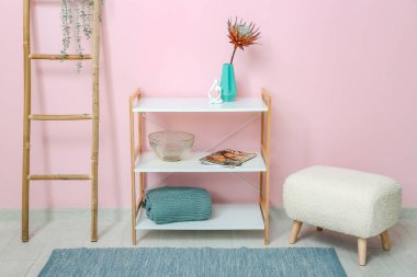 Kurumuş kırmızı proteli vazo, raf ünitesi ve pembe duvarın yanındaki merdiven.