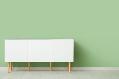 Yeşil duvarın yanındaki beyaz çekmeceler çok şık.