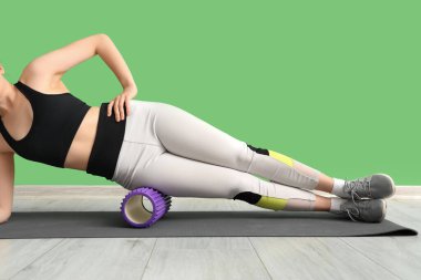 Spor salonunda köpük silindirli genç kadın eğitimi.