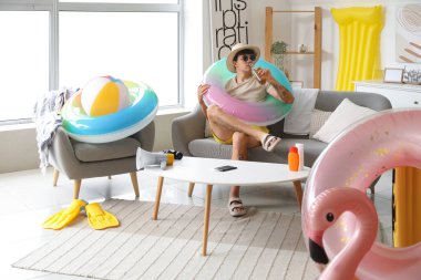 Bira ve plaj aksesuarları olan genç adam yaz tatiline evde hazır.