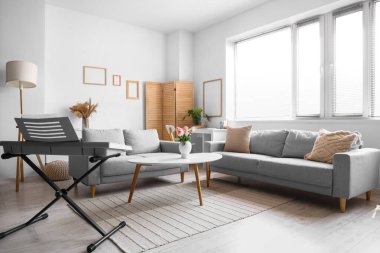 Koltukları ve sentezleyicisi olan bir oturma odası.