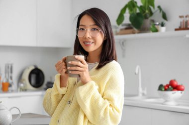 Mutfakta bir fincan lezzetli çayla güzel bir Asyalı kadın.