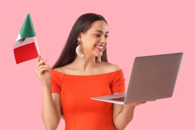 Pembe arka planda Meksika bayrağı ve laptopu olan genç bir kadın.