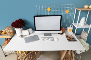 Modern bilgisayarlı, kasımpatı çiçekli ve balkabaklı rahat bir iş yeri.