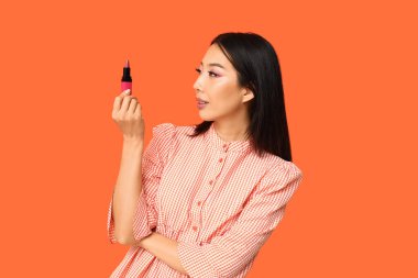 Turuncu arka planda ruj izi olan güzel bir Asyalı kadın.