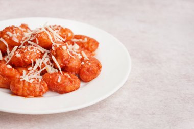 Beyaz arka planda peynirli lezzetli bir gnocchi tabağı.