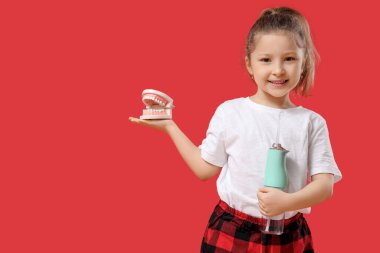 Kırmızı arka planda ağız sulandırıcısı ve çene modeli olan tatlı küçük kız.