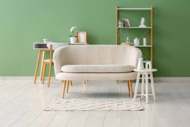 Oturma odasında raf ünitesi ve halı olan rahat beyaz bir kanepe.