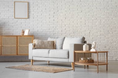 Oturma odasındaki pencerenin önünde kahve masası olan rahat gri kanepe.