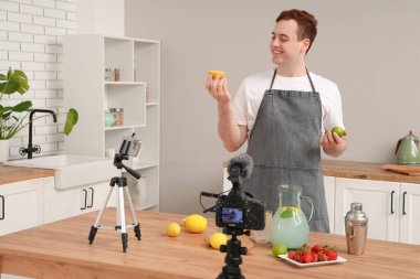 Genç adam onun mutfakta ev yapımı limonata yaptığını videoya kaydediyor.