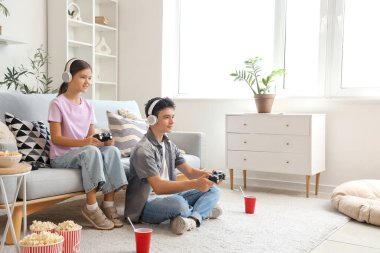 Erkek kardeşi ve kulaklığı evde video oyunu oynuyor.